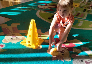 Dziecko turla dynię po miedzy pachołkami