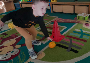 Dziecko turla dynię po miedzy pachołkami