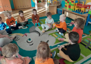 Dzieci podają sobie w zabawie dynię