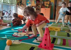 Dziecko turla dynię po miedzy pachołkami