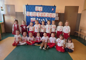 Dzieci ubrane na biało czerwono pozują na tle dekoracji z okazji obchodów święta niepodległości.