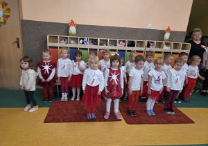 Dzieci ubrane na biało czerwono z okazji obchodów święta niepodległości ustawione są do hymnu.