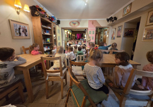 Dzieci w baśniowej kawiarence siedzą i oczekują na początek przedstawienia.