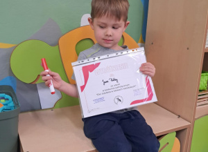 Dziecko trzyma dyplom i upominek