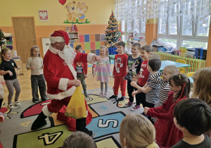 Mikołaj tańczy z dziećmi w sali przedszkolnej