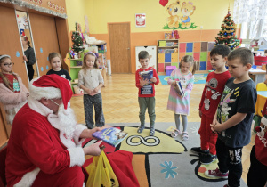 Mikołaj podaje dzieciom książki
