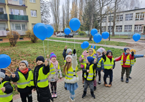 Dzieci idą w parach z niebieskimi balonami w ręku