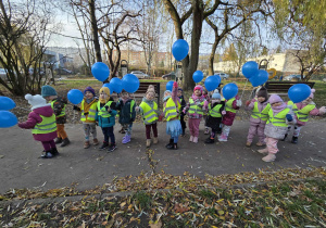 Grupa dzieci na dworze z niebieskimi balonami w ręku