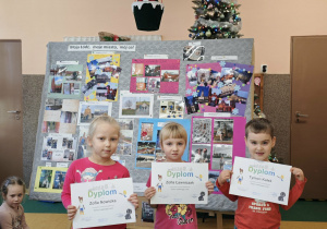 Troje dzieci stoi z dyplomami