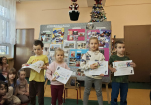 Czworo dzieci stoi z dyplomami i nagrodami