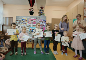Siedmioro dzieci stoją razem z paniami na środku ssli