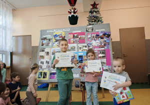 Troje dzieci stoi na tle fotografii