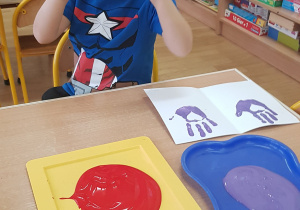 Dziecko podczas malowania - stemplowania dłoni w farbie.