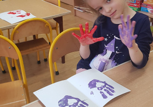 Dziecko podczas malowania - stemplowania dłoni w farbie.