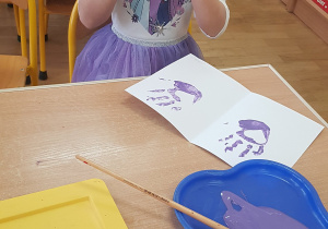 Dziecko podczas malowania - stemplowania dłoni w farbie.