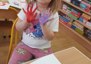 Dziecko podczas malowania - stemplowania dłoni w farbie.