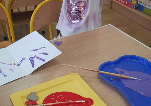 Dziecko podczas malowania - stemplowania dłoni w farbie.
