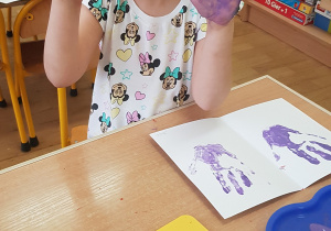 Dziecko podczas malowania - stemplowania dłoni w farbie.