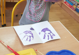 Dziecko podczas malowania - stemplowania dłoni w farbie.