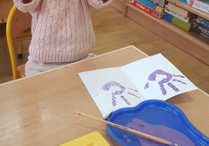 Dziecko podczas malowania - stemplowania dłoni w farbie.