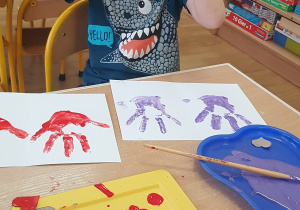 Dziecko podczas malowania - stemplowania dłoni w farbie.