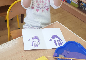 Dziecko podczas malowania - stemplowania dłoni w farbie.