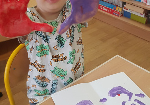 Dziecko podczas malowania - stemplowania dłoni w farbie.