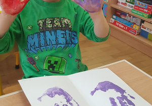 Dziecko podczas malowania - stemplowania dłoni w farbie.