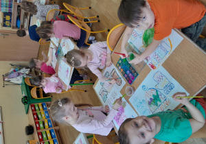 dzieci siedzą przy stole i rysują