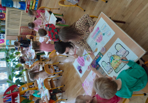 dzieci siedzą przy stole i rysują