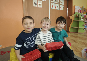 Trzech chłopców siedzi na kanapie z klocków