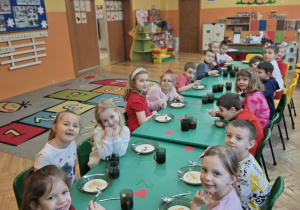 Dzieci siedzą przy długim zielonym stole