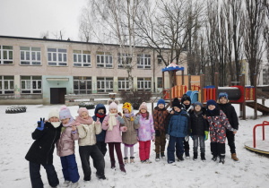 Dzieci w zimowych ubraniach w ogrodzie przedszkolnym