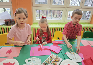 Dzieci wykonują pracę plastyczną z różowych kartek