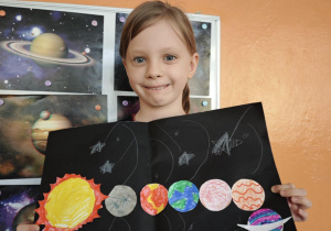 Dziewczynka trzyma w rękach narysowany Układ Słoneczny