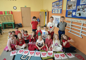Dzieci siedzą obok napisu walentynki