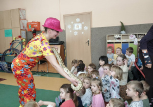 Pani w kolorowym stroju pokazuje dzieciom węża
