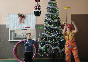 Chłopiec i pani klaun kręcą na patykach talerzami