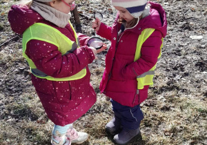 Dziewczynki oglądają przez lupę.