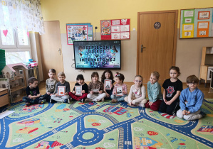 Dzieci pozują do zdjęcia na tle ekranu z prezentacją o bezpieczeństwie w Internecie