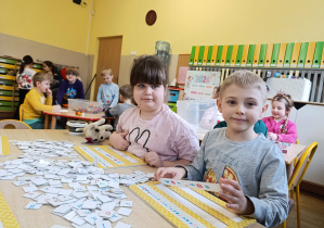 Dziewczynka i chłopiec rozkodowują i czytają wyrazy.