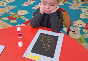 Chłopiec patrzy się na swoją pracę