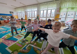 Dzieci wykonują ćwiczenia które pokazuje nauczycielka