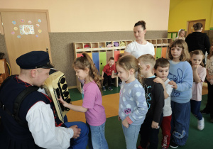 pan w ludowym stroju pokazuje dzieciom akordeon