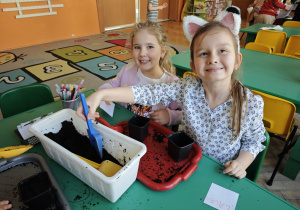 Dwie dziewczynki wsypują do ziemię do doniczek