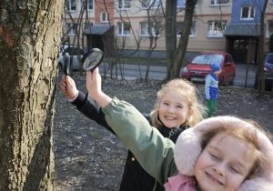 Dwie dziewczynki oglądają kore drzewa przez lupę