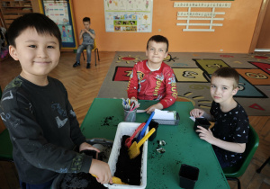 Chłopcy wsypują ziemię do doniczek