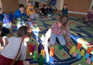 Dzieci uczestniczą w zajęciach z wykorzystaniem kolorowych kubeczków