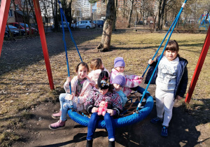 Dzieci siedzą na huśtawce typu bocianie gniazdo