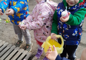Dzieci pokazują pisanki do zabawy w poszukiwanie jajek wielkanocnych.